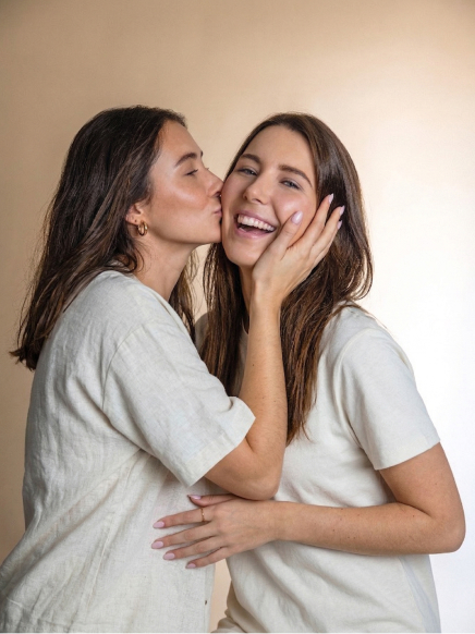 A woman kissing her friend on the cheek.